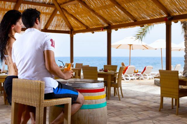 Ľudia v bari pri bazéne v The Cove Rotana Resort