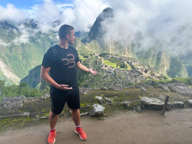 Náš  sprievodca s nadšením ukazuje na ruiny Machu Picchu, odhaľ